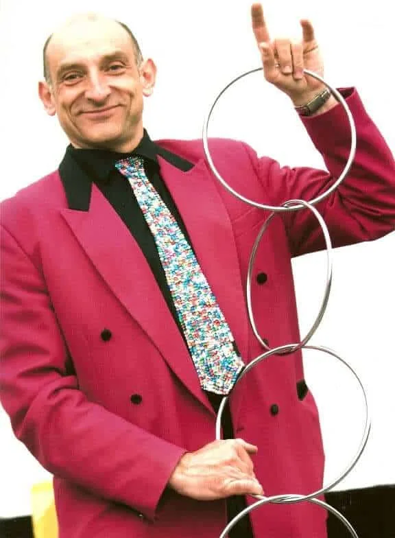 Mr Tinsel in a red jacket holding linking rings