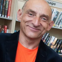 Mr Tinsel smiling, in a dark jacket and orange T-shirt